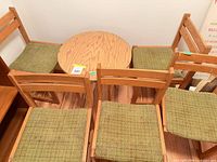 four light wood chairs with green upholstered seats