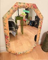 Full view of octagonal mirror showing floral frame and reflection