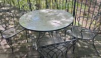 round wrought iron patio table with four matching chairs on deck