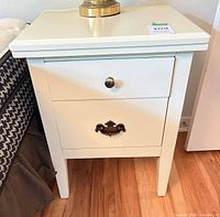 Front view of white nightstand beside bed