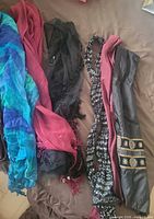 First group of scarves on bed: blue-green ruffle, burgundy, black bead, black-white paisley, dusty rose, grey with gold