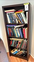 Front view of tall dark brown wooden bookcase with books (contents excluded)