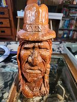 Front view of carved wooden Indigenous elder bust showing facial detail and hat