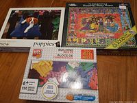 All three boxed items on floor: White Mountain 1000-pc puzzle, puppies 750-pc puzzle, Block Tech 250-pc bricks