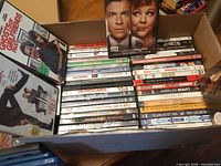 Box of DVDs and Blu-rays showing spines with multiple identified titles