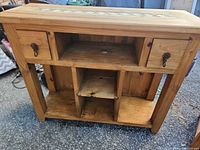 Front view of pine console table showing drawers, open shelves, overall form