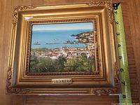 Front view of framed painting with measurement tape showing width around 8 in