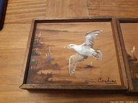 left painting showing seagull in flight, signature visible