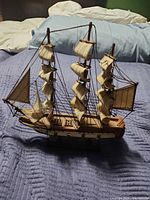 Port side view of wooden model ship on its stand showing sails and rigging