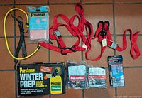 All items arranged on floor: Prestone kit, Rope Ratchet packs, cam straps, bungees, sponge, Loctite kit