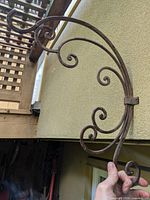 Single wrought iron scrollwork bracket held up to wall