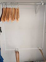 Wire frame organizer installed under closet rod with wooden hangers shown on both upper and lower tiers
