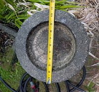 Top view of concrete bird bath basin with tape measure showing roughly 11 inch diameter