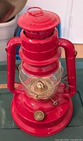 Front view of red Dietz Little Wizard lantern showing globe, burner, frame