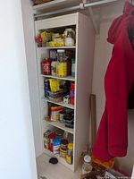 Front view of white Ikea shelving unit showing five shelf positions with contents for scale