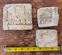 Front view of three ceramic relief tiles with ruler for scale