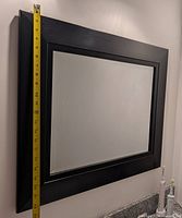 Front view of the black wooden framed mirror mounted on wall