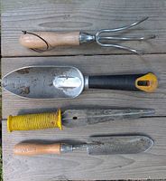 Four hand digging tools laid out on wood surface
