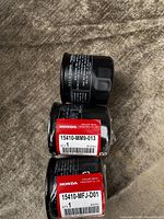 Stack of three sealed Honda oil filters showing two red parts labels