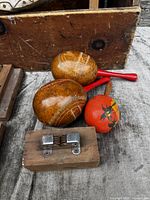 View of two natural gourd maracas, painted maraca, and wood block knife sharpener on wooden surface