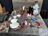 Overall view of lot showing tumblers, dolls, snowman, bowl, ornaments on tabletop