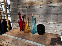 Group view of red, amber, teal bottles and black vase