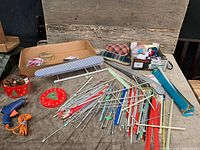 tabletop view of knitting needles, rulers, glue gun, tin and craft items