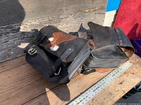 Pair of leather saddlebags on wooden surface showing overall form and yoke