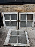 Three rustic four-pane pine windows with original hinges displayed