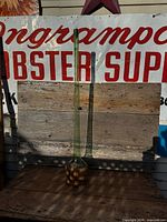 Full view of tall green glass bottle on table against sign