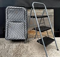 Suitcase next to folded out ladder displaying full view of both items