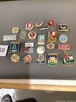 Group of 18 Soviet enamel pins displayed on grey surface