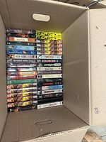 Open box showing two stacks of assorted VHS tapes with visible spines