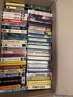 Box filled with stacked VHS tapes showing titles such as Lost Horizon, Sabrina, The Haunting and others