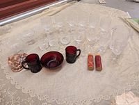 Entire lot laid out on cloth showing crystal stemware, pitcher, cranberry glassware, candles, seashell