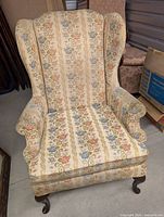 Full view of wingback armchair showing upholstery pattern and wood legs