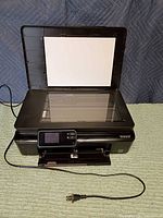 Printer with lid open showing scanner bed and power cord