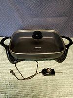 Full view of Presto electric skillet with lid, handles, legs and probe cord