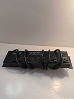 Front view showing eight AC outlets and coiled power cord