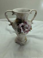 Full view of vase front showing applied flower, handles, pedestal