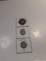 Front view of three coins in labeled cardboard flips