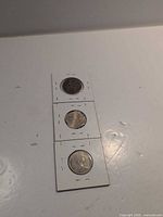 Front of three stapled coin holders showing obverse sides
