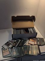 Long box open with rows of Magic cards inside and spread in front