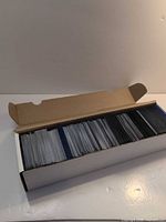 Open long box with rows of unsleeved cards