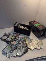 Spread of sleeved Magic cards, black deck box, Commander Legends booster box