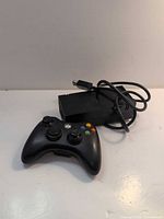 Black Xbox controller with power brick visible