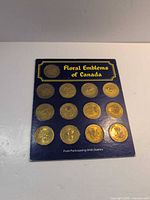 Card side labelled Floral Emblems of Canada with 15 brass tokens mounted