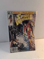 Front view of bagged Spider-Woman #50 comic showing full cover art and $1.25 price