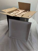 Closed black box opened showing packed square white plate in front
