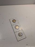 Three coins in holders, top to bottom 1944, 1947, 1949
